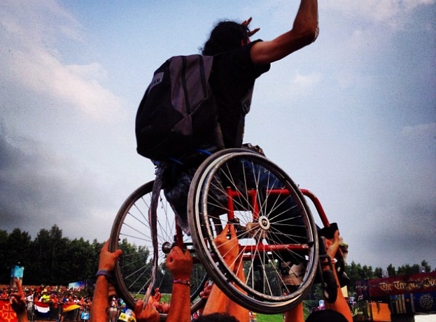 foto van een persoon in een rolstoel die boven het festivalpubliek wordt getild 