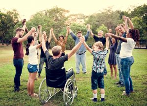 Persoon in een rolstoel houd handen vast met andere mensen in een cirkel